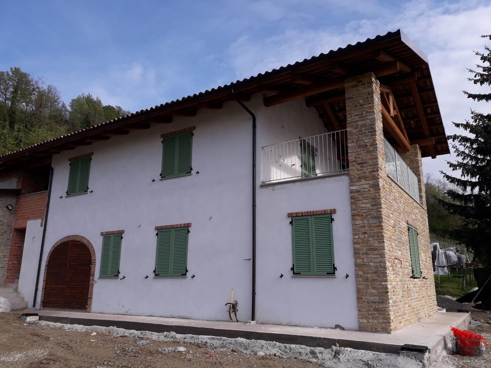 La cascina d'insieme: persiane verdi su tutte le aperture e portone in noce