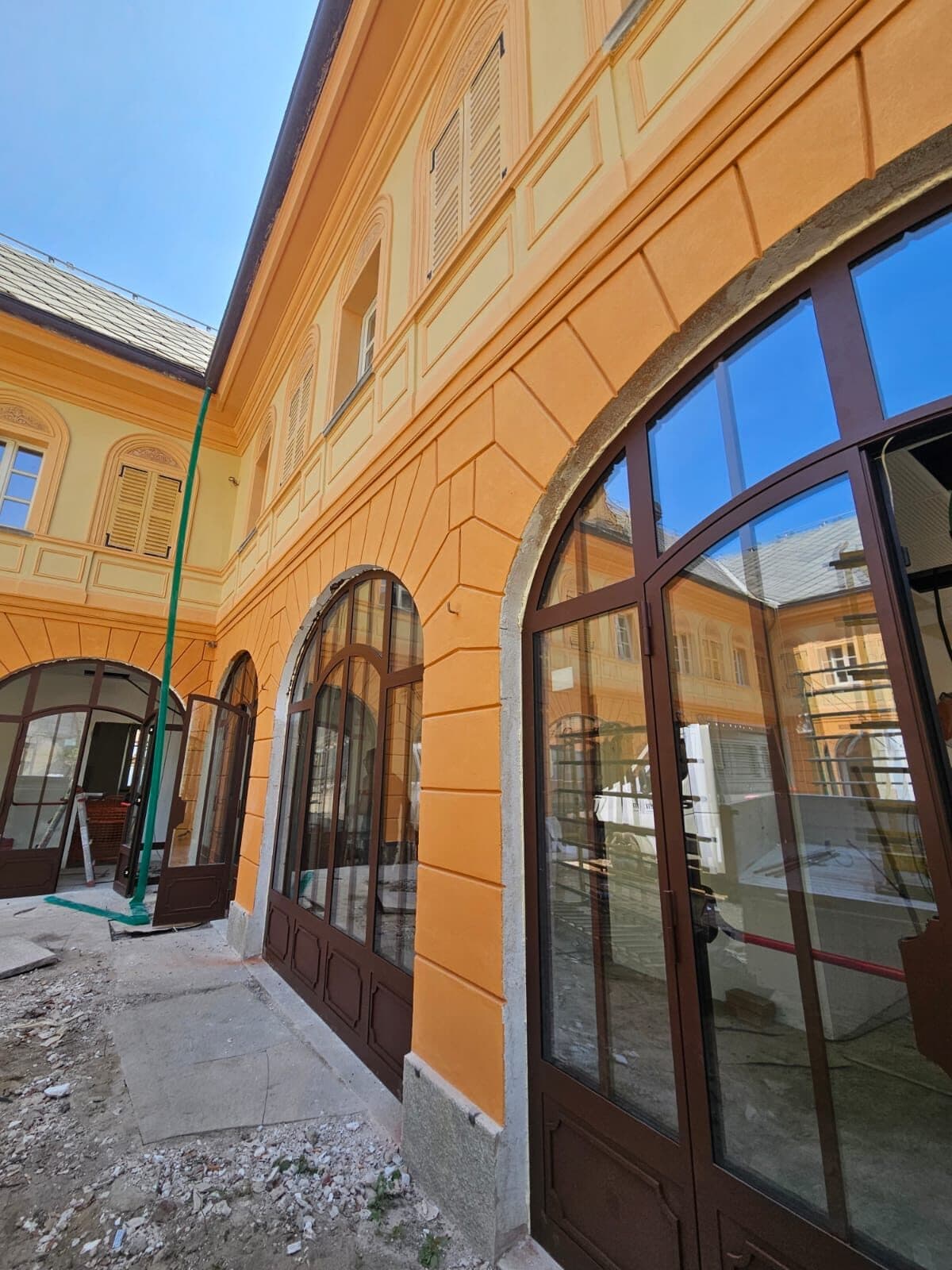 Corte porticata di un palazzo storico, con le arcate chiuse da portali vetrati in alluminio color bronzo