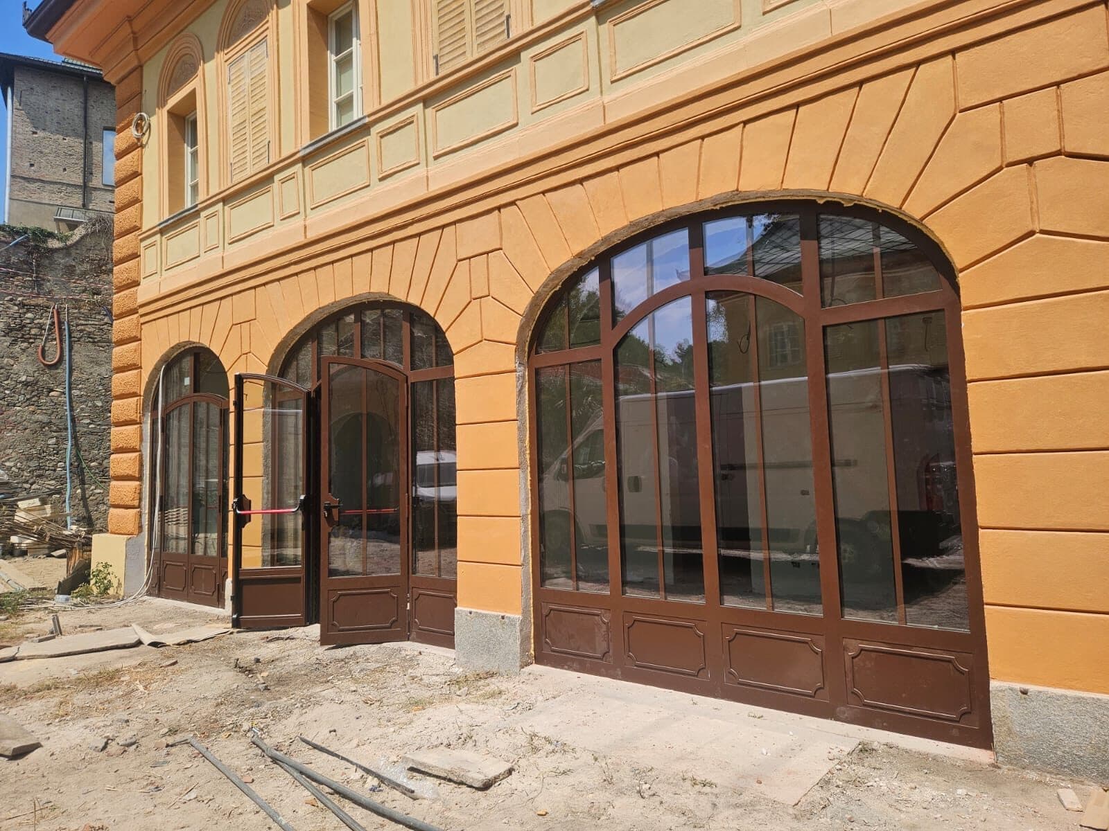 Corte di un palazzo storico restaurato, con portali ad arco in alluminio color bronzo sotto il portico