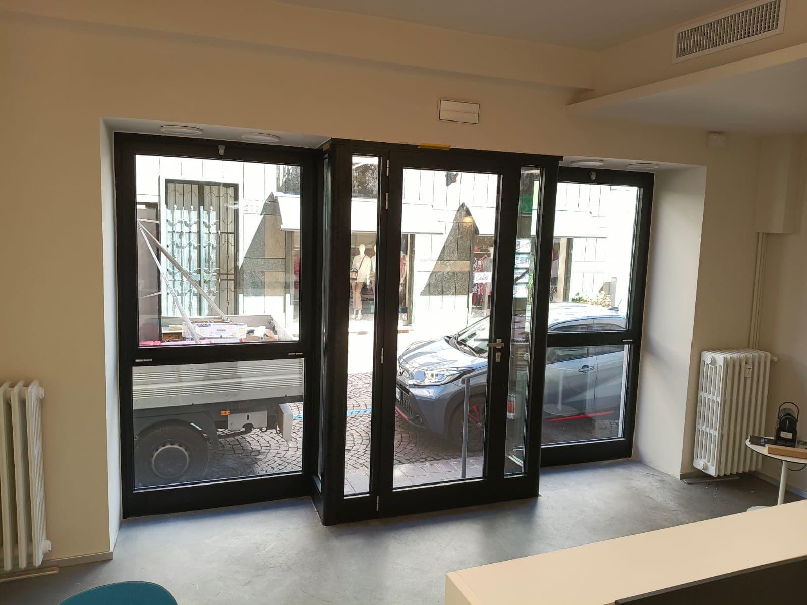 La vetrina vista dall'interno, di fronte: la porta d'ingresso con i fissi laterali fra le due specchiature