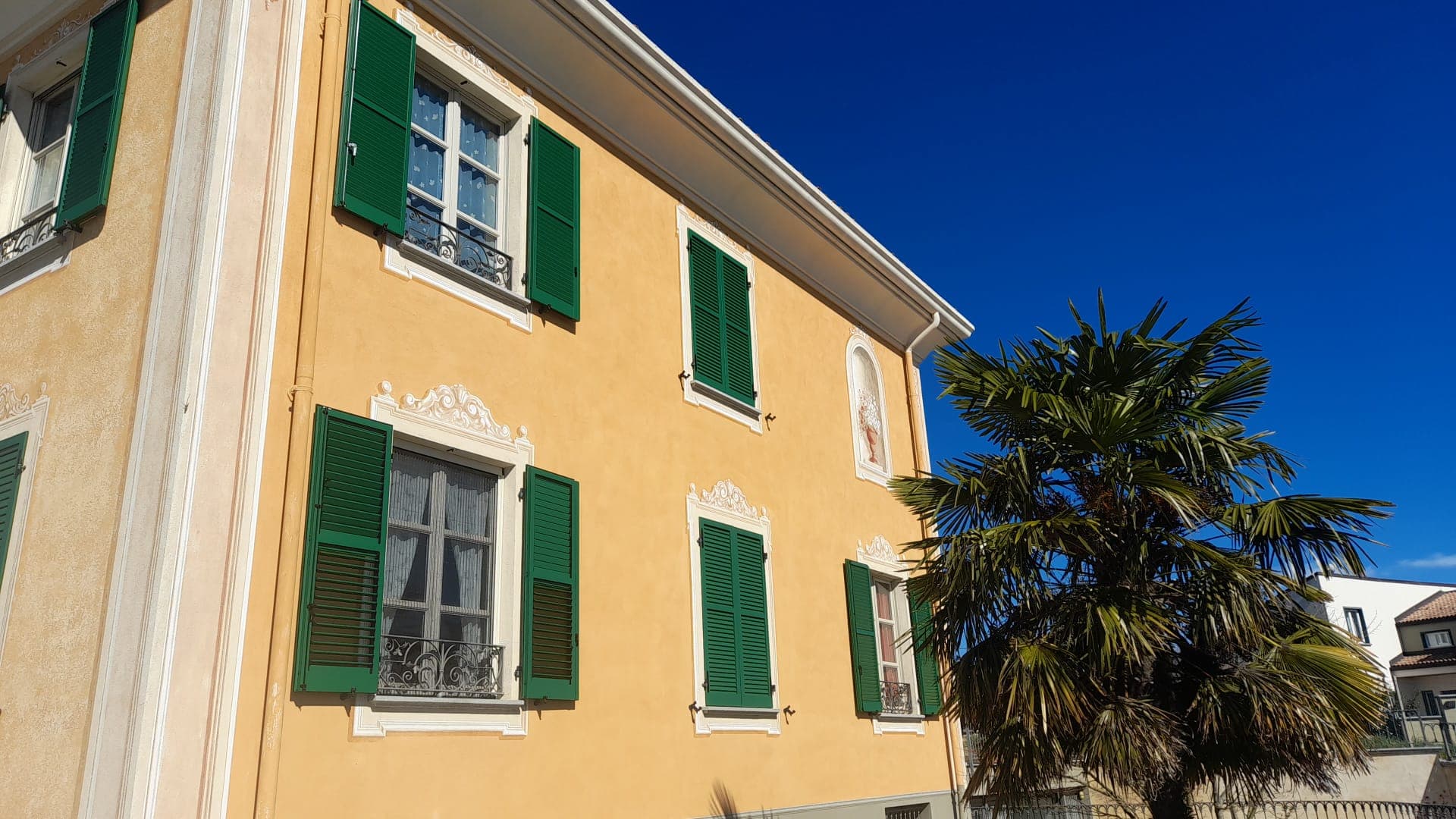 Facciata della villa con due ordini di finestre con persiane verdi